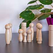 Eine Gruppe von Holzfiguren eines Familienbretts vor einer Pflanze.