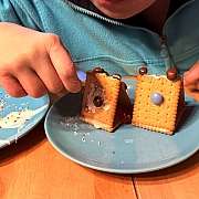 Ein Mensch mit Beeinträchtigung dekoriert Kekse mit Süßigkeiten und Zuckerguss.