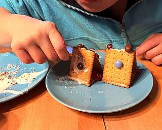 Ein Mensch mit Beeinträchtigung dekoriert Kekse mit Zuckerguss und Süßigkeiten.