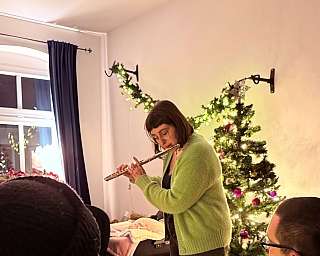 Eine Frau spielt Flöte, während andere zuhören.